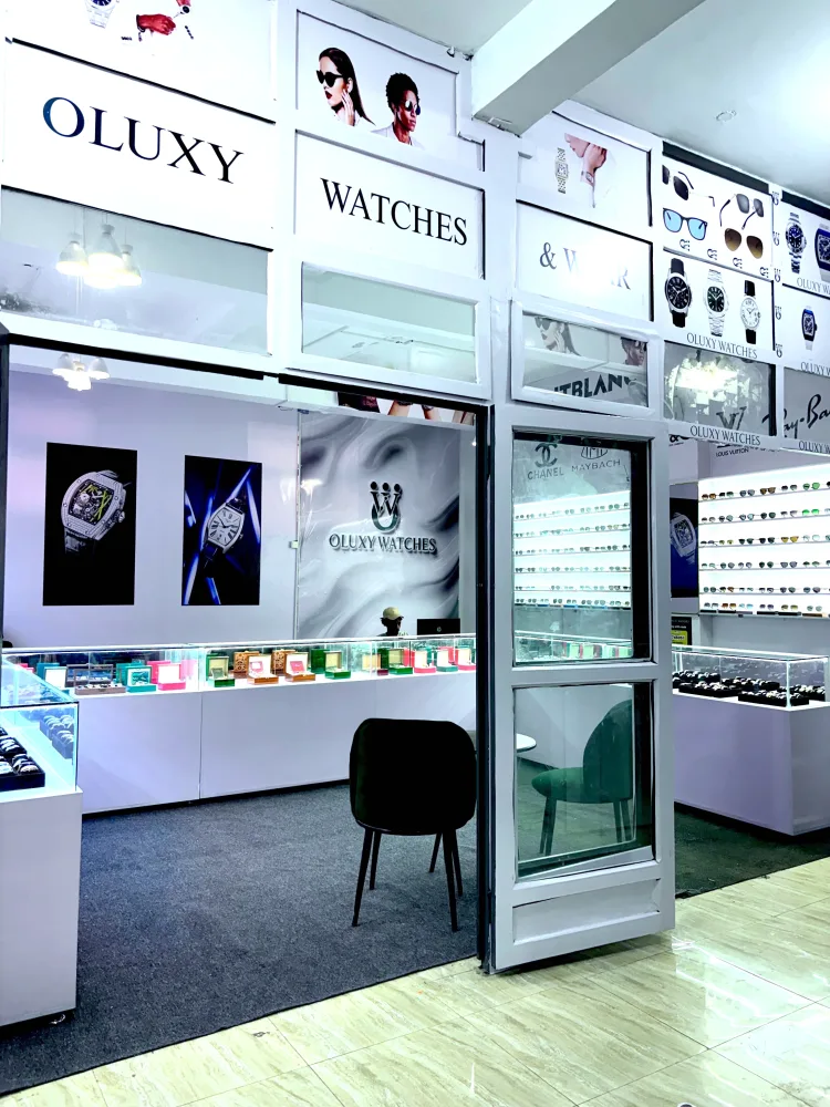 The front of the Oluxy Watches & Wear shop at GF Plaza: the white sign over the door, lit glass counters inside, sunglasses on the wall to the right